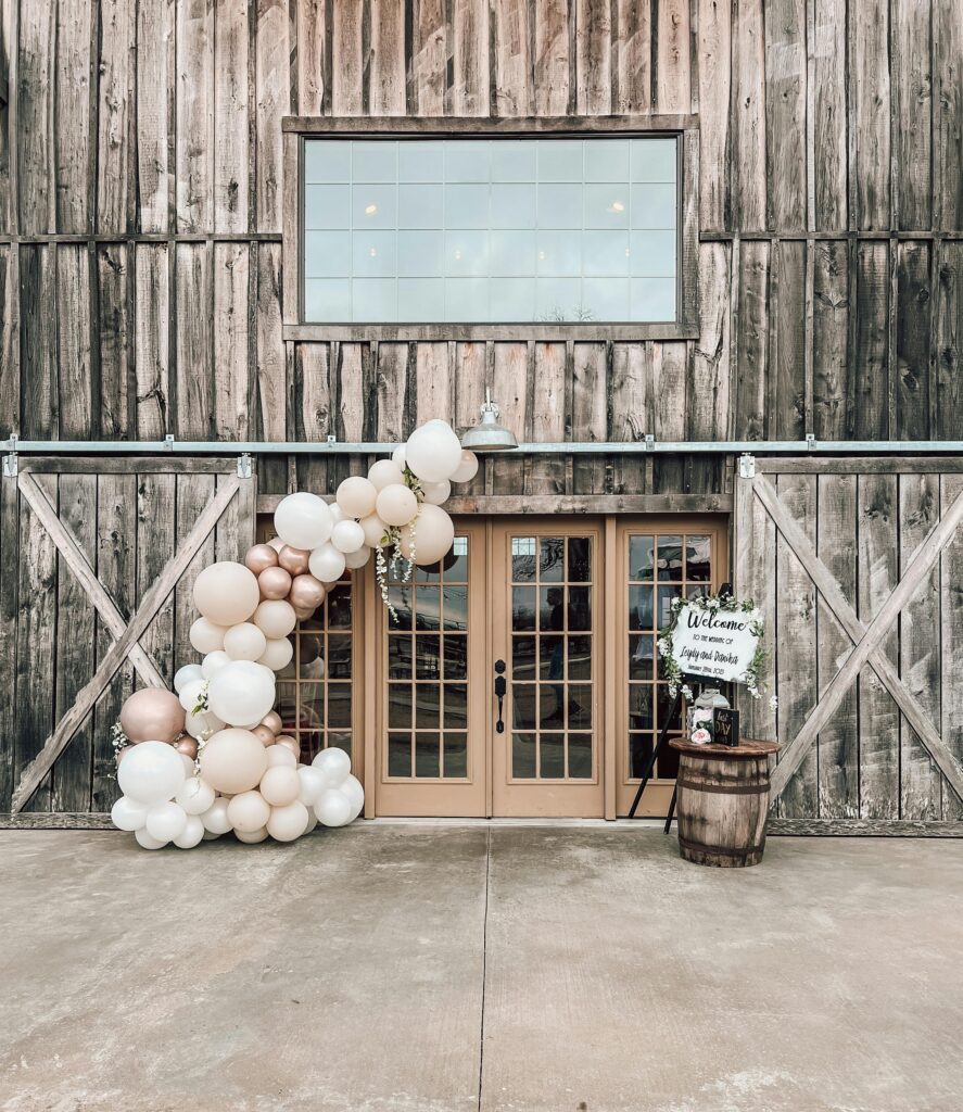 Charming rustic entrance decor with balloons and wooden accents, ideal for weddings.