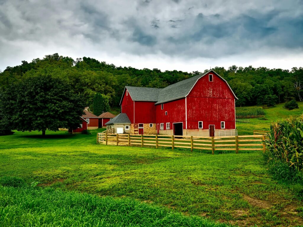 Vibrant red barn amidst lush greenery and cloudy skies in Wisconsin.